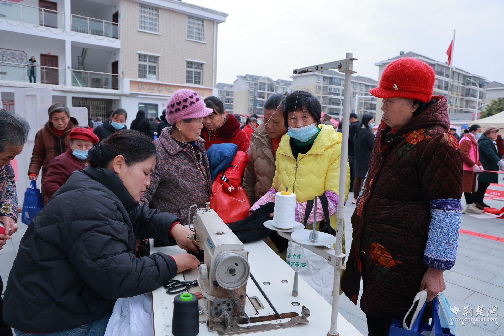 衣物縫補(bǔ)攤前，志愿者飛針走線為居民修補(bǔ)破損衣物.jpg.jpg